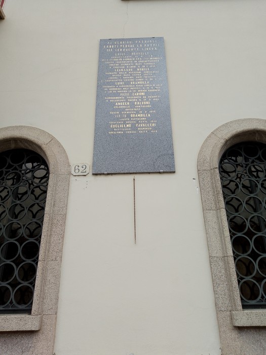 Lapide commemorativa ai partigiani su una parete, con nomi e date in memoria dei caduti.
