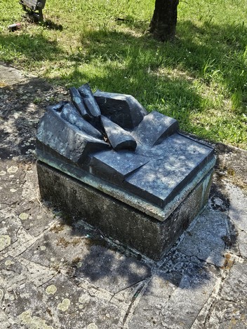 Monumento alla Resistenza, scultura in bronzo su base di pietra, immersa nel verde circostante.