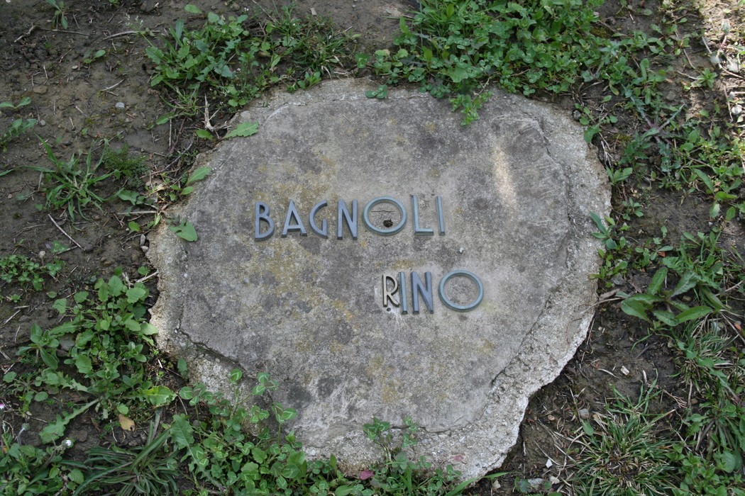 Monumento commemorativo nel cimitero di Stia, dedicato a Rino Bagnoli, immerso nel verde.