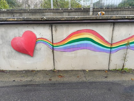 Murale colorato a Pioppe con un grande cuore rosso e una striscia di colori arcobaleno.
