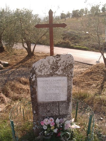 Cippo commemorativo dedicato a Giannelli e alle Pecci, situato in un paesaggio rurale.