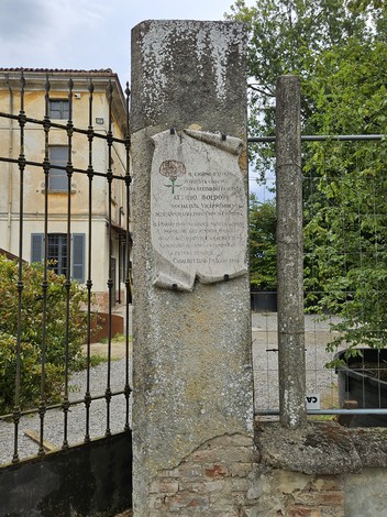 Lapide commemorativa a Boldori, inserita in un contesto storico con vegetazione e architettura circostante.