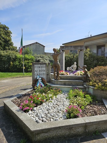 Monumento commemorativo con sculture, fiori e bandiera italiana, dedicato ai caduti di Fombio.