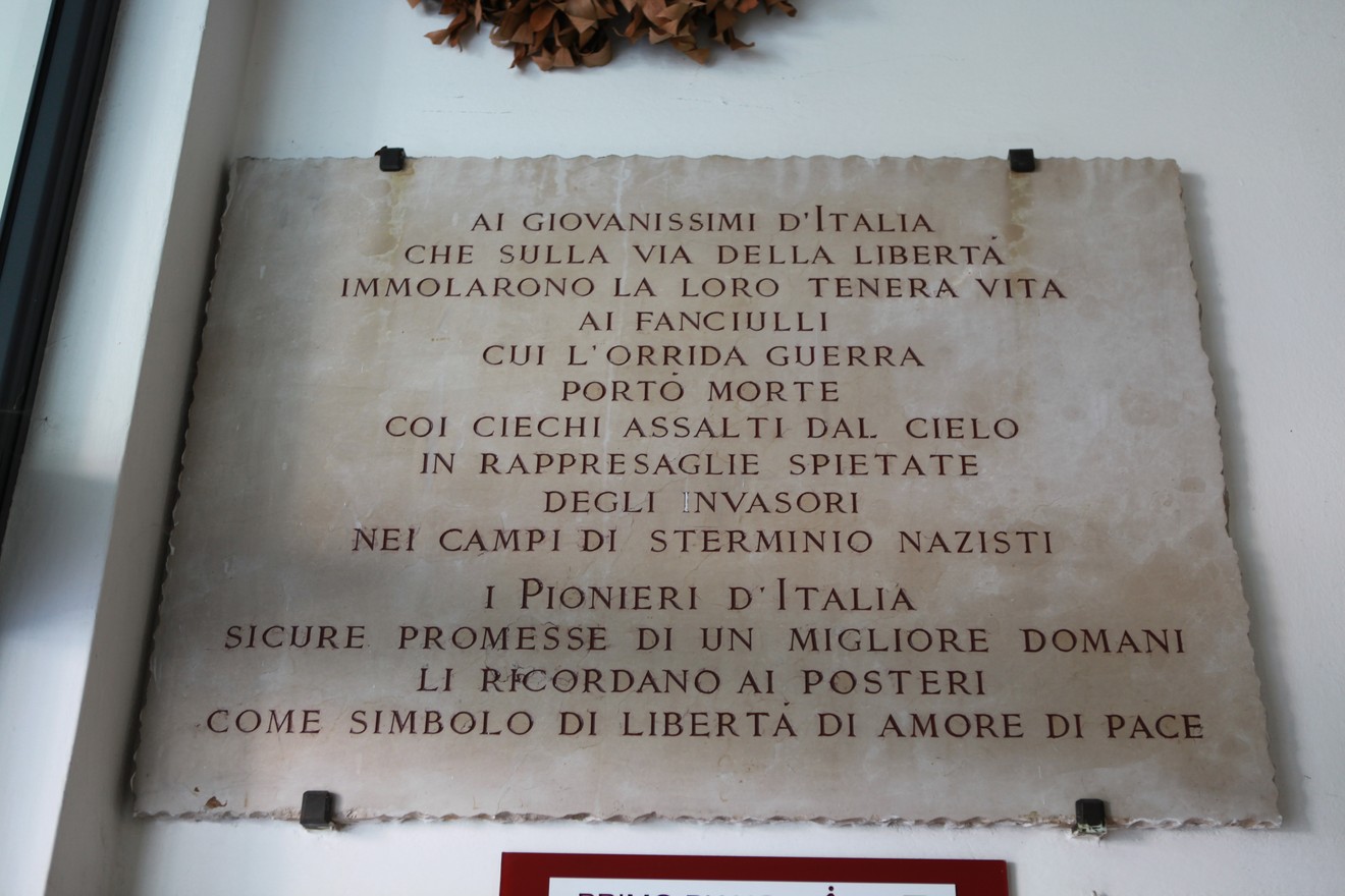 Lapide commemorativa in memoria dei giovani caduti per la libertà, con incisioni di grande significato storico.