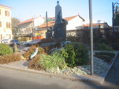 Monumento ai caduti circondato da verde, commemorativo e situato in un'area urbana.
