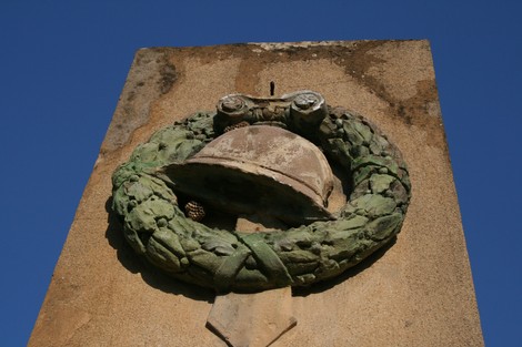 Monumento ai caduti di Ugnano, incorniciato da una corona di alloro e un elmetto, simbolo di memoria e rispetto.