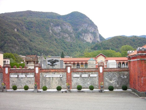 Monumento commemorativo ai fucilati, situato nel cimitero, con sfondo naturale montano.