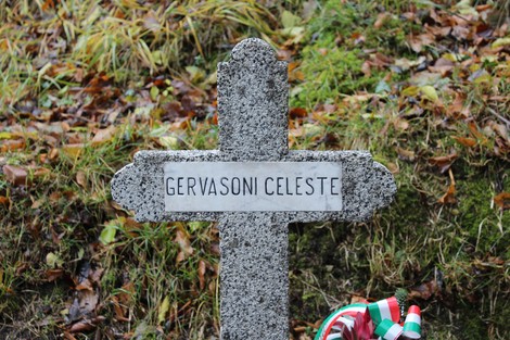 Croce commemorativa in pietra con il nome Gervasoni Celeste, circondata da foglie autunnali.