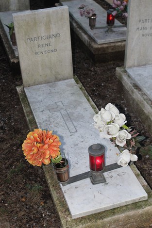 Tombe di partigiani decorate con fiori e candele, in onore dei caduti per la libertà.