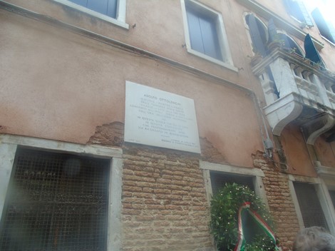 Lapide dedicata a Ottolenghi, situata su un muro di un edificio a Venezia, con elementi decorativi e un omaggio floreale.