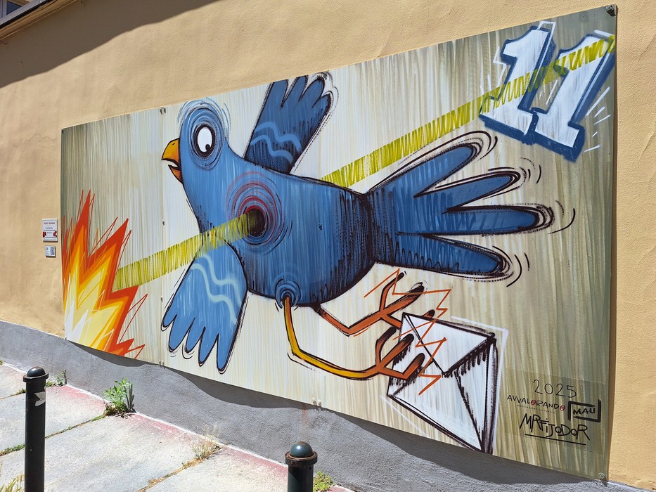 Murale colorato di un uccello blu che vola, emettendo raggi di luce e fiamme, con un messaggio visivo creativo.