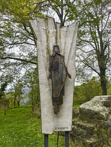 Statua rappresentante il Cristo Risorto nella Via Crucis di Casaglia, immersa nella natura.