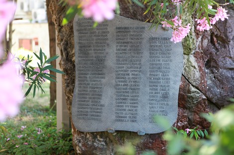 Monumento ai caduti del Lido, commemorazione con elenco di nomi su una superficie rocciosa, contornato da fiori.
