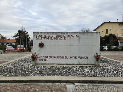Monumento in memoria dei caduti per la libertà e le vittime del nazifascismo, decorato con fiori e corona.