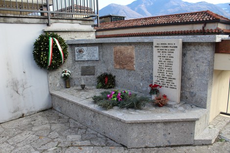 Monumento commemorativo con dettagli in pietra e fiori freschi, dedicato ai fratelli Pellegrini.