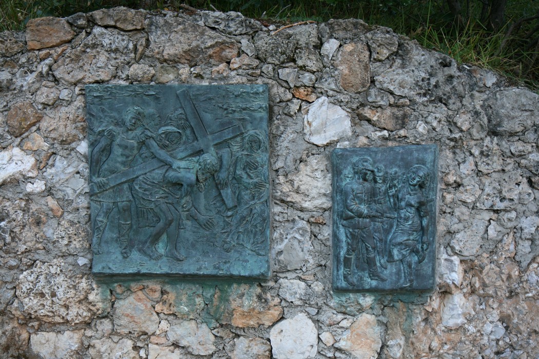 Rappresentazione della Via Crucis di Sant'Anna di Stazzema, con sculture di bronzo su sfondo roccioso.