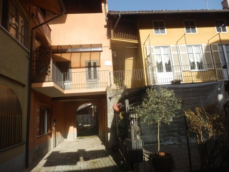 Lapide commemorativa in un cortile storico, con edifici in stile architettonico tradizionale.
