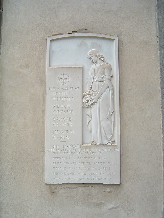 Lapide commemorativa nel cimitero comunale, decorata con un rilievo che rappresenta una figura femminile in omaggio ai defunti.