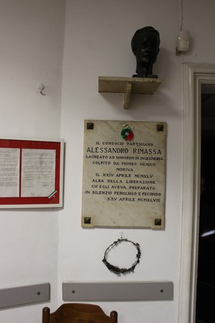 Lapide commemorativa dedicata a Alessandro Rimassa, con busto, in un ambiente storico.