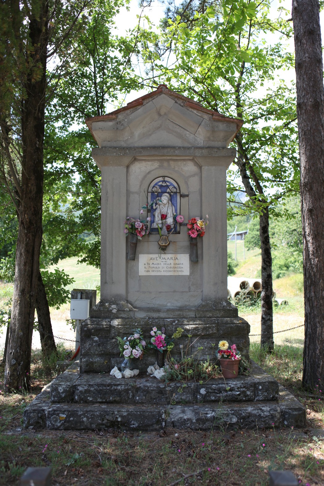 Tabernacolo di Caburaccia, monumento decorato con fiori, immerso nel verde, simbolo di devozione locale.
