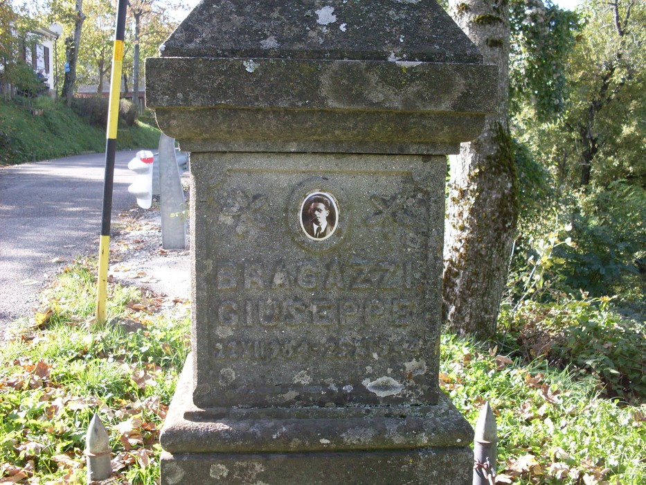 Cippo commemorativo dedicato a Giuseppe Bragazzi, situato a Torri, in un contesto naturale e tranquillo.