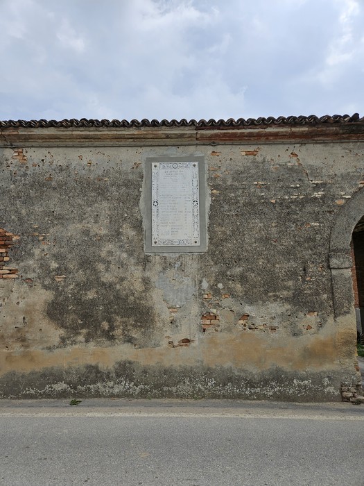 Lapide commemorativa che ricorda i Martiri di Cavezzo, affissa su una parete esterna.