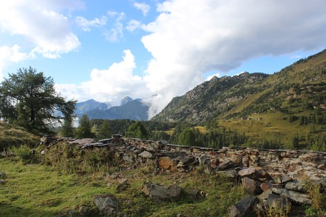 Panorama del Vecchio rifugio dei Laghi Gemelli immerso nella natura montana con vette e nuvole.