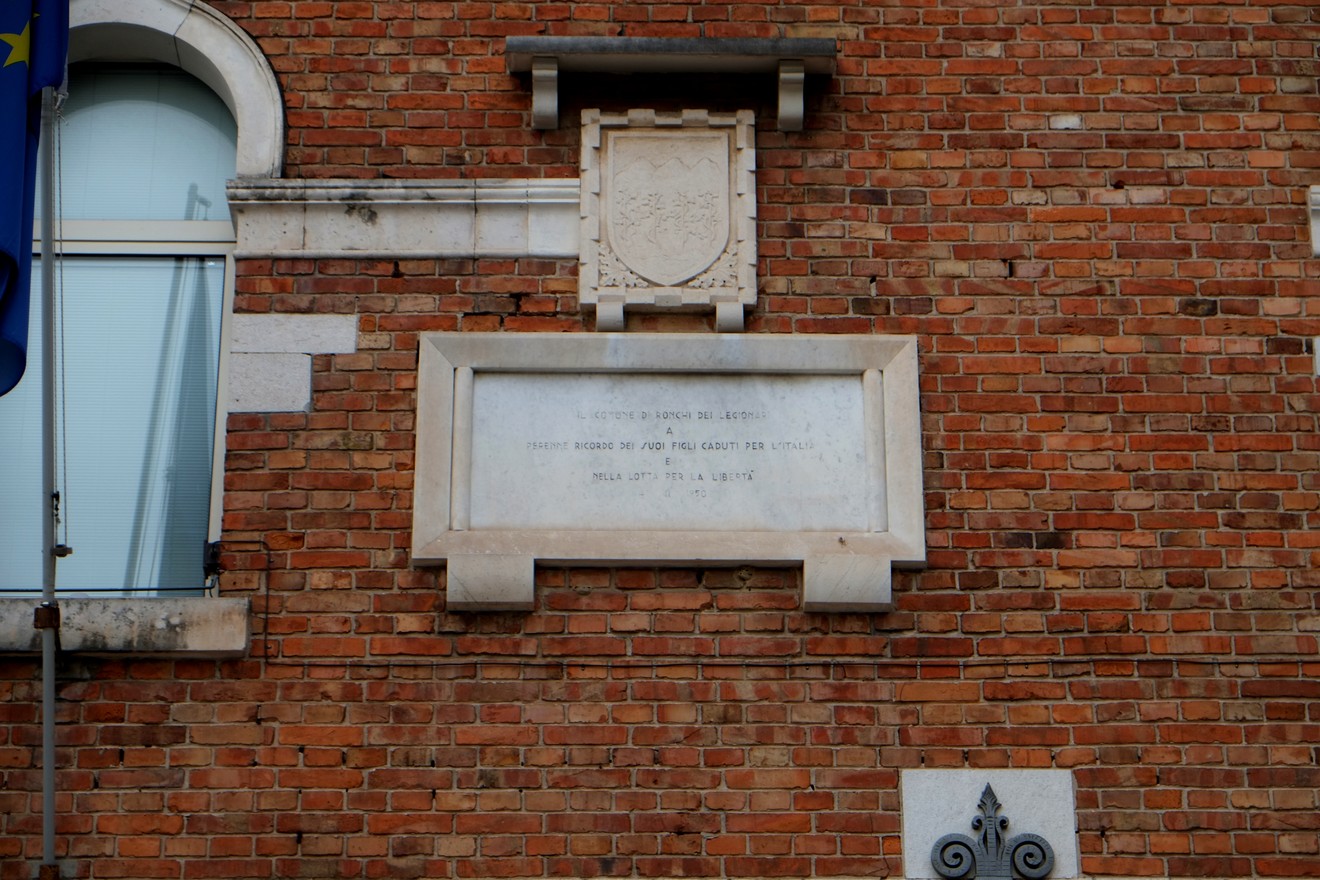 Lapide commemorativa in memoria dei caduti, situata su una facciata in mattoni.