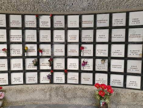 Monumento Ossario dedicato ai caduti partigiani, con placche commemorative e fiori.