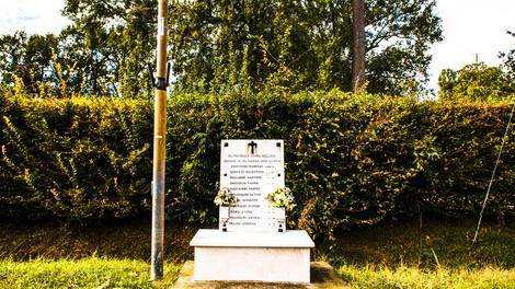 Monumento commemorativo ai caduti nel bombardamento, con fiori e incisi i nomi delle vittime.