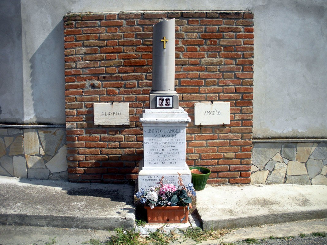Monumento commemorativo con base in pietra e decorazioni floreali in memoria di Vedaschi.