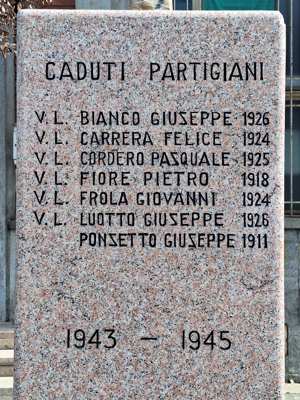 Monumento ai caduti con nomi incisi su una stele commemorativa in marmo, dedicato ai partigiani.