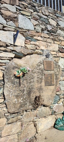 Lapide commemorativa per i caduti di Maffiotto, con fiori e un ambiente di pietra circostante.