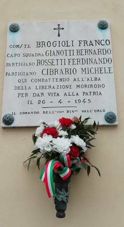 Lapide commemorativa dedicata a Brogioli, Gianotti, Cibrario e Rossetti, con un omaggio floreale sotto di essa.