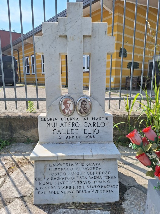 Cippo commemorativo dedicato ai martiri Mulatero Carlo e Callet Elio, con fotografie e decorazioni floreali.