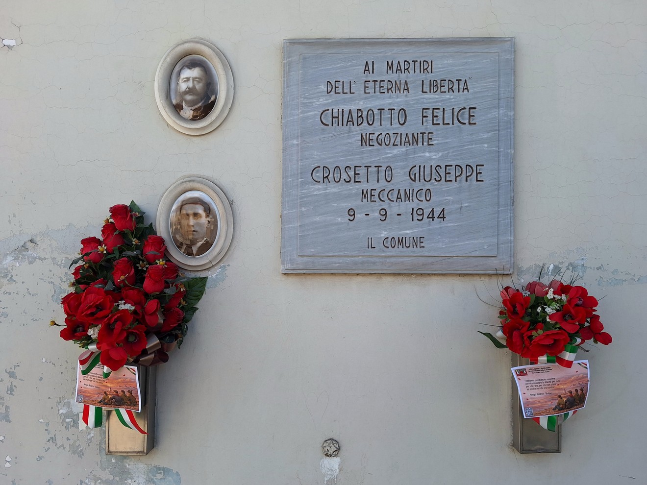 Lapide commemorativa a Chiabotto e Crosetto, con fiori rossi ai lati e due medaglioni ritrattistici.