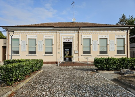 Lapidi commemorative ai caduti, affiancate da un edificio con finestre e un giardino curato.