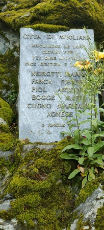 Lapide commemorativa dedicata a Neirotti e altri, immersa nella natura, in memoria di coloro che hanno dato la vita.