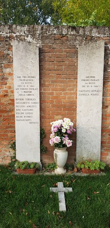 Lapidi commemorative degli uccisi della Certosa, con fiori e croce, in un'atmosfera di memoria e rispetto.