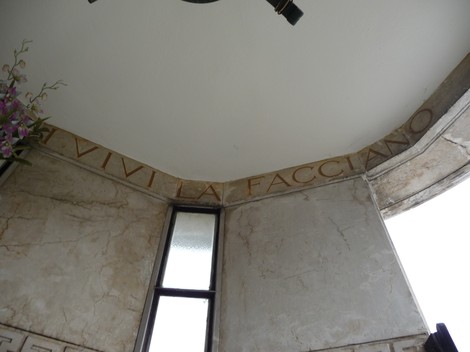 Interno del "Sacrario ai caduti partigiani" con pareti in pietra e decorazioni floreali.
