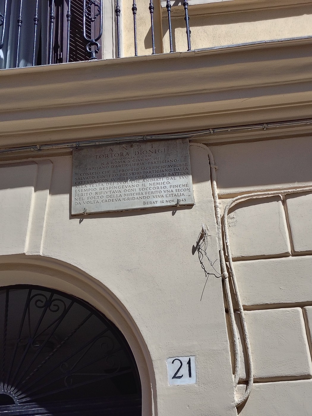 Lapide commmemorativa su un edificio di Tortora, con affresco architettonico in stile classico.