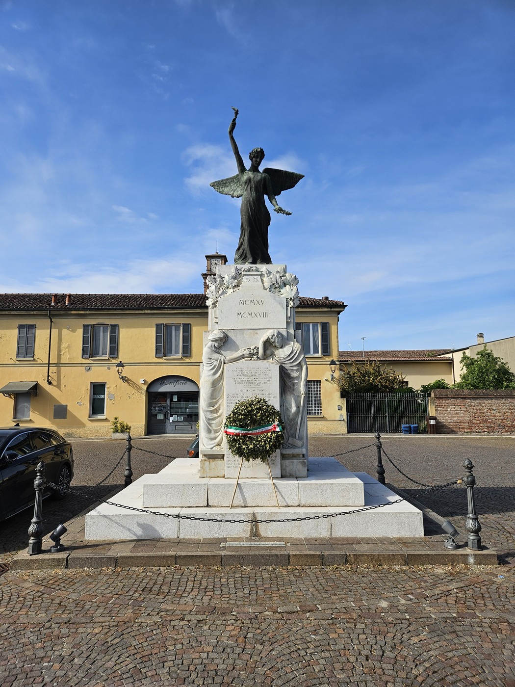 Monumento ai Caduti di San Giovanni in Croce con statua di angelo e decorazioni floreali.