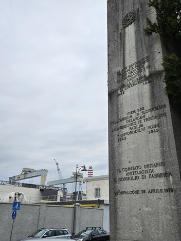 Monumento commemorativo ai cantierini caduti, dedicato alla guerra di Liberazione, con sfondo industriale.