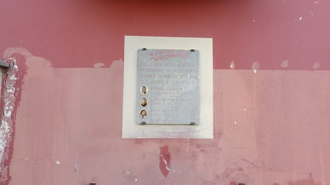 Lapide commemorativa che onora Lapide a Pomba, Mascherpa e Boccardo, affissa su una parete rossa.