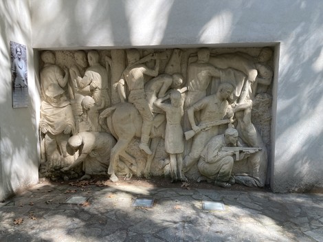 Scena raffigurante la lotta e il sacrificio dei partigiani, con figure scolpite in movimento e intensità drammatica.