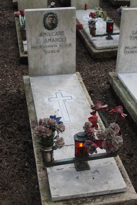 Tombe con croci, fiori e lumini commemorativi per i caduti per la Libertà, in un cimitero.