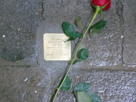 Pietra d'inciampo dedicata a Marco Righi con una rosa rossa posata accanto.