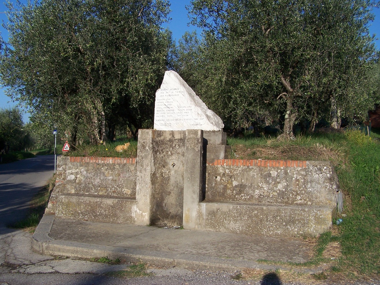 Cippo di San Gennaro, monumento circondato da ulivi, visibile lungo una strada di campagna.