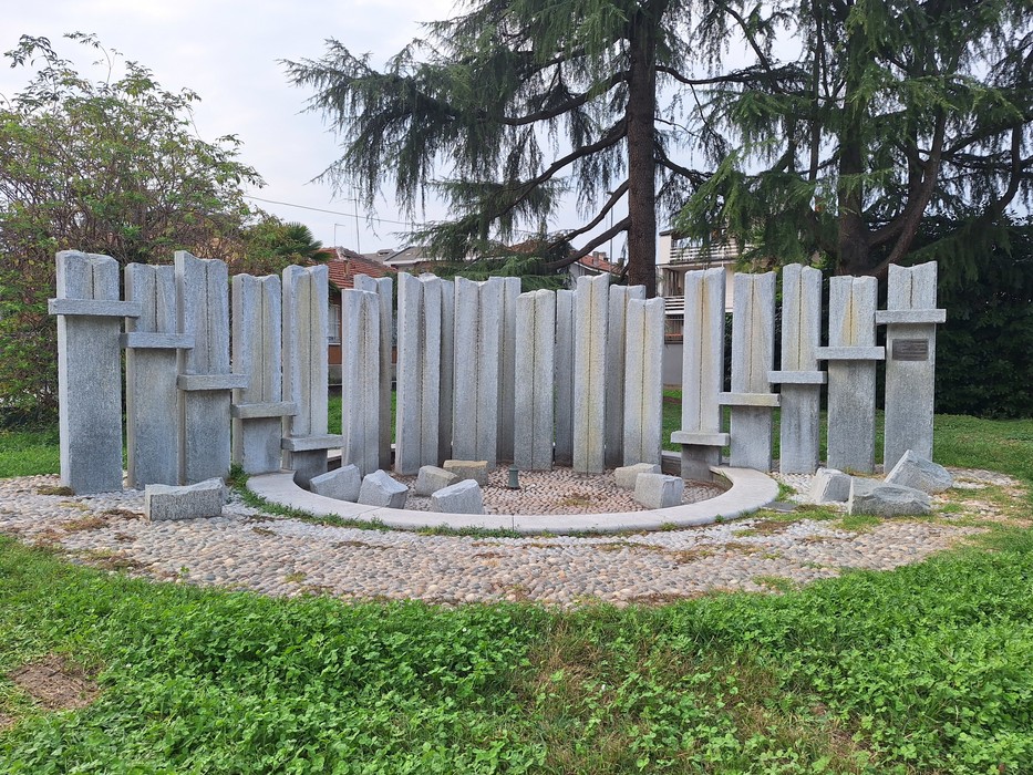 Monumento composto da alte lastre verticali di pietra disposte in cerchio, in un giardino con alberi.
