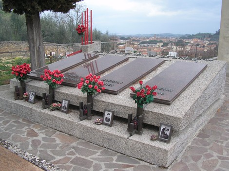 Sepolcro dedicato ai partigiani, con lapidi e fiori rossi in memoria dei caduti.